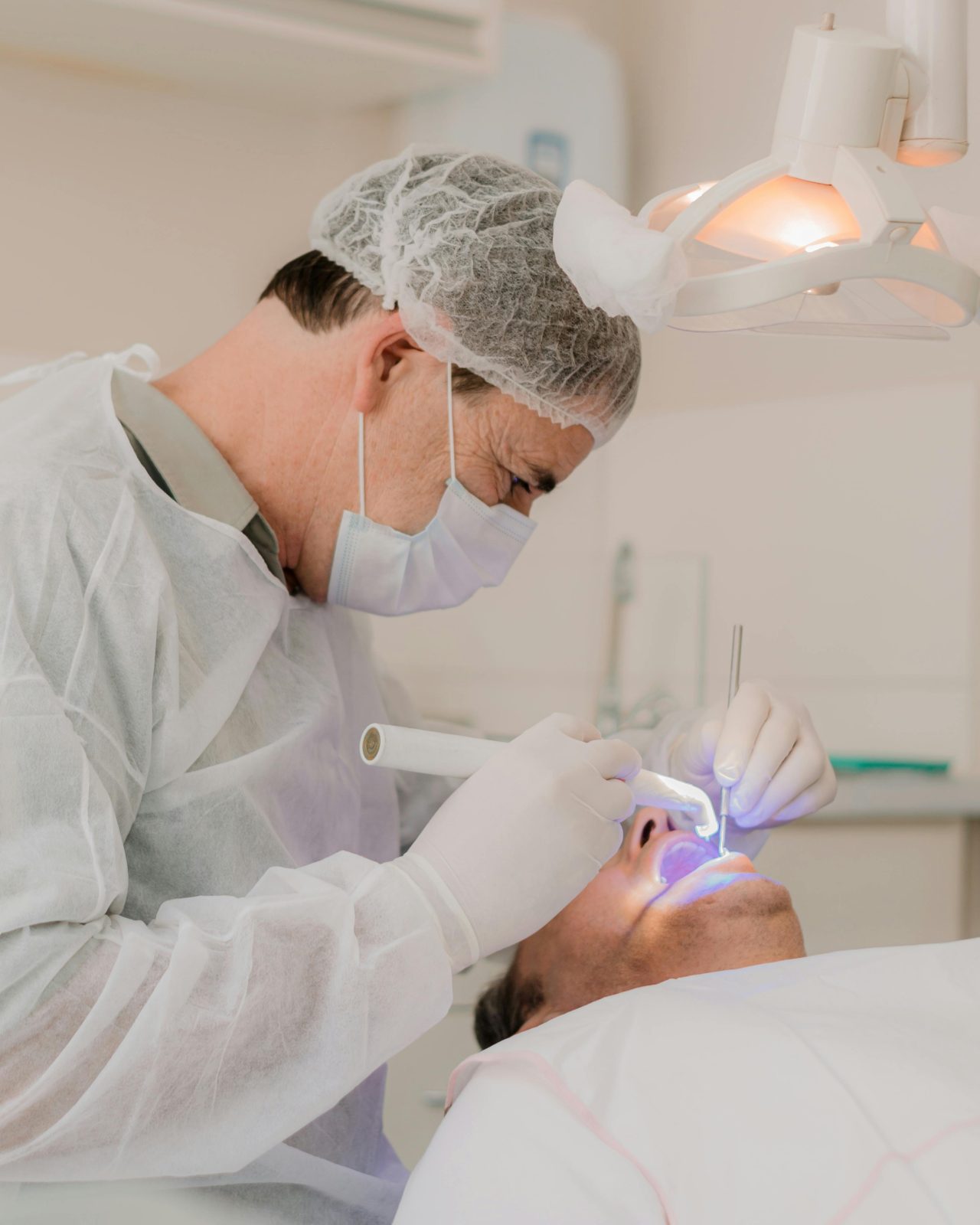 Dentista segurando luz led no dente do paciente.