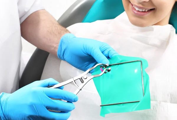 Dentista ajustando isolamento absoluto antes de colocar na boca da paciente