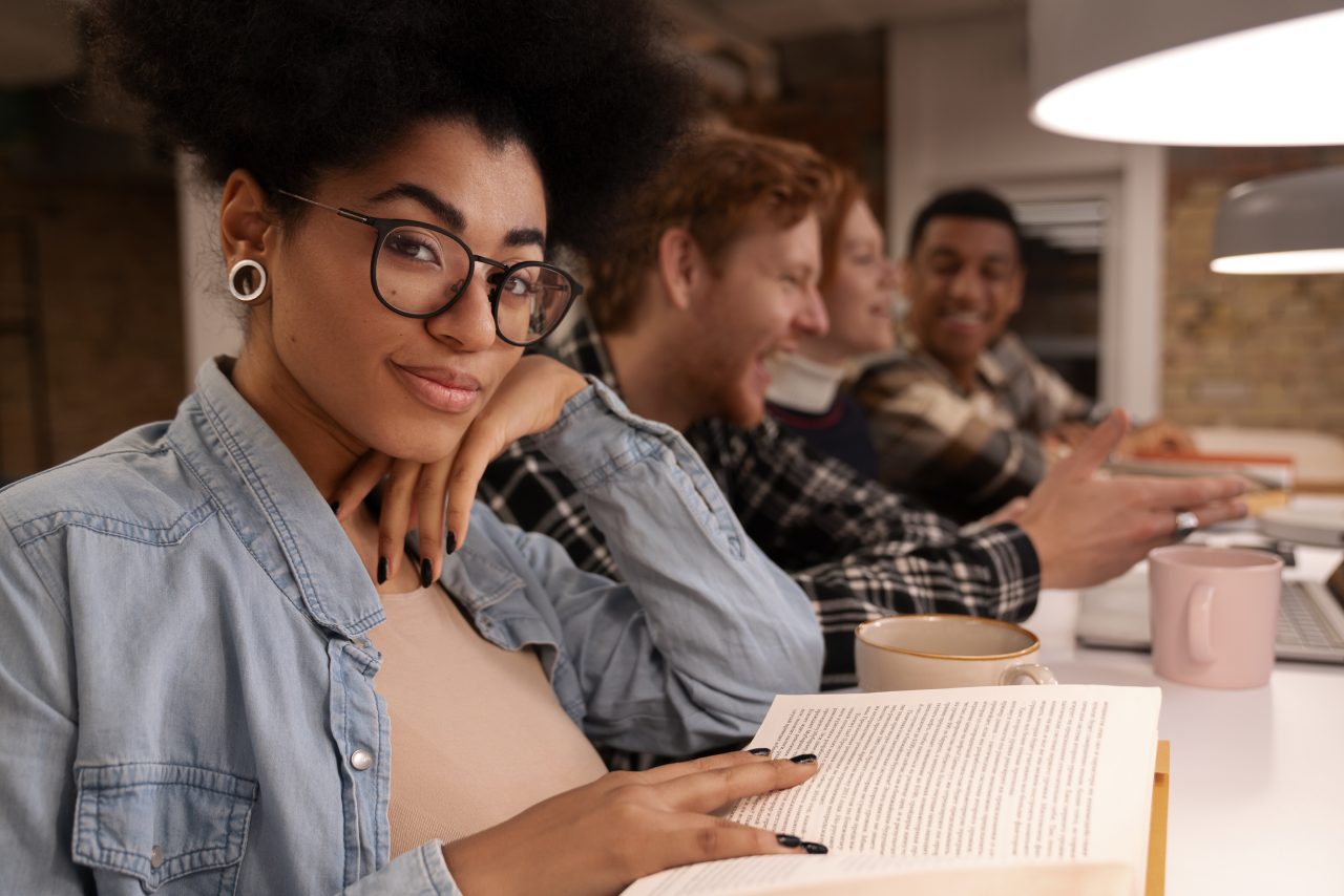 Alunos estudando juntos lado a lado em biblioteca.