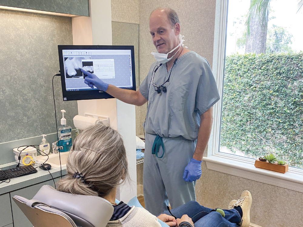 Dentista explicando procedimento com imagens para senhora.