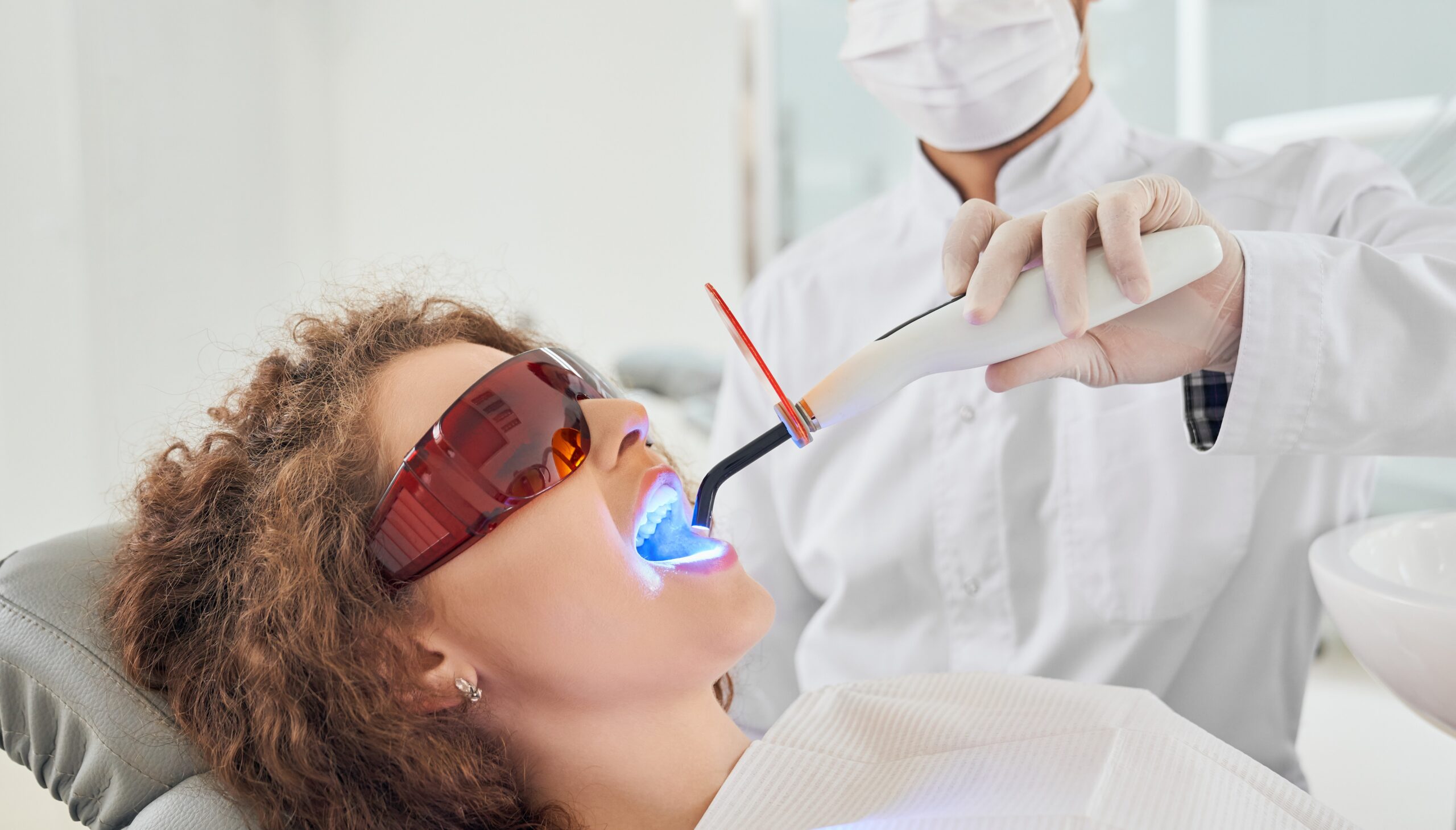 dentista utilizando fotopolimerizador nos dentes do paciente