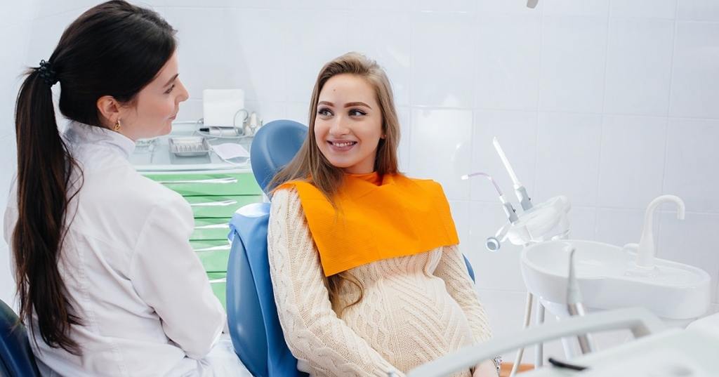 Grávida na dentista falando com dentista