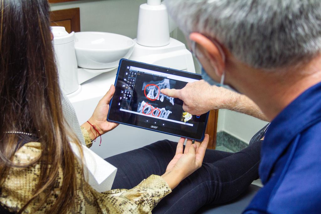 médico dentista apontando na imagem dentes para paciente