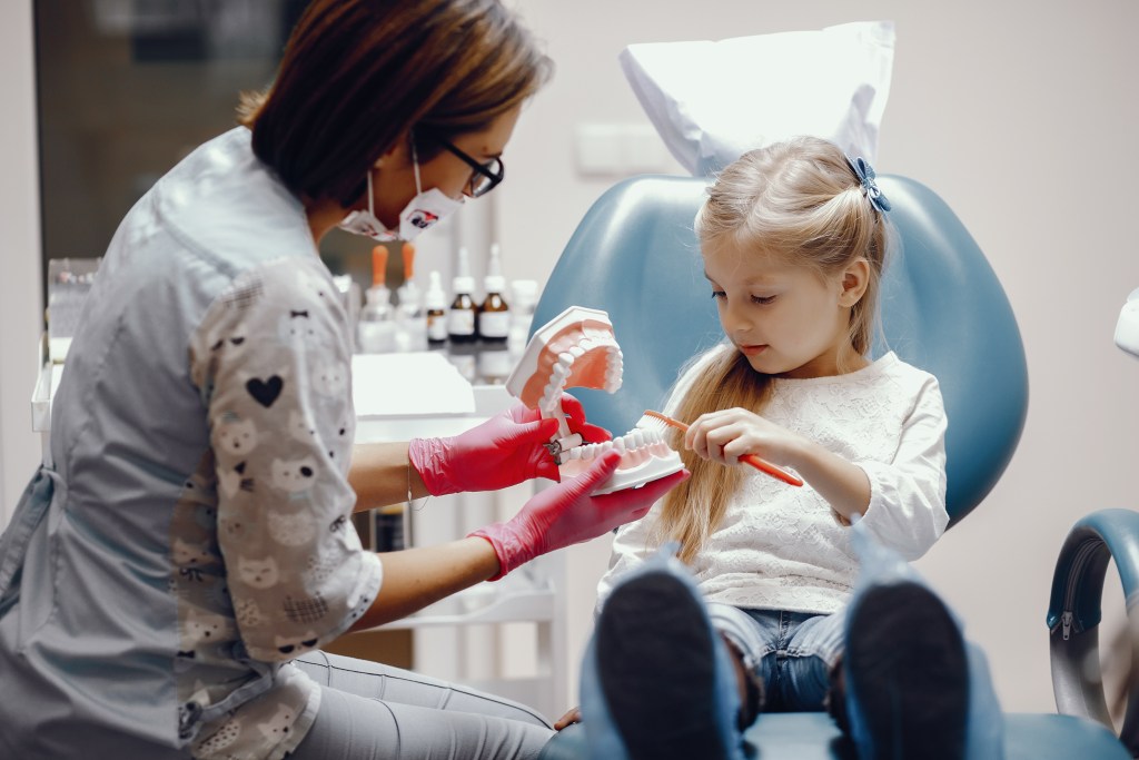 dentista mostrando para criança como escova os dentes através de um molde