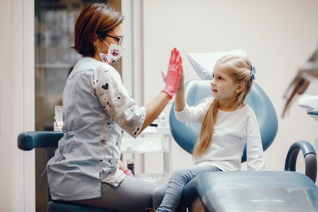 garotinha e dentista batendo suas mãos