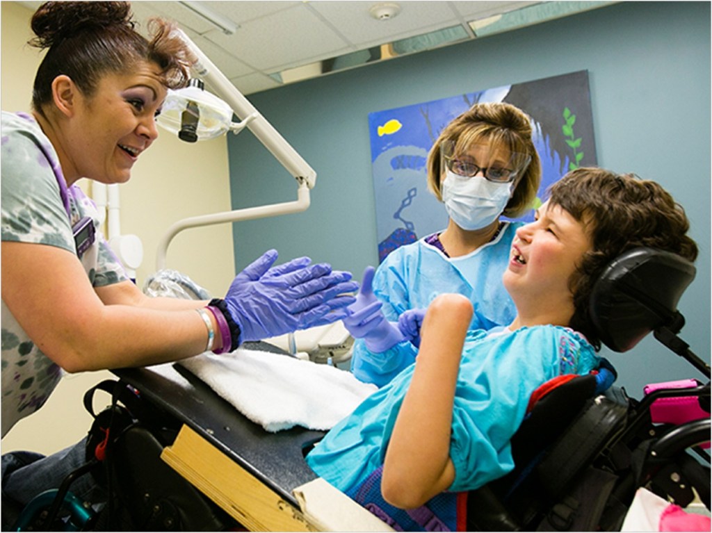 criança com deficiência em uma cadeira de rodas especial inclinada no dentista