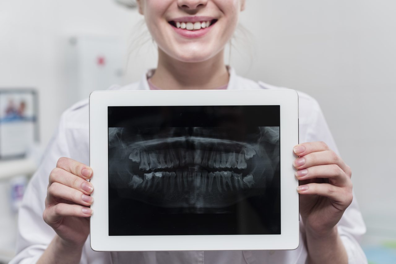 dentista com raio x da boca de paciente em tablet