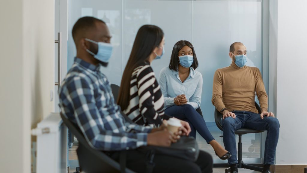 pessoas esperando na sala de espera do consultório usando máscara