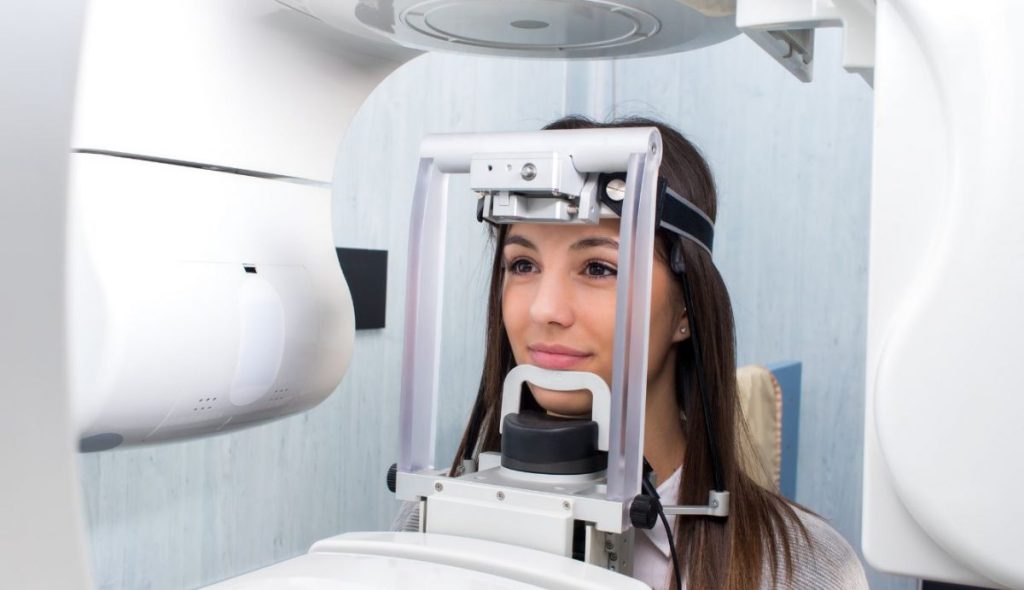 Mulher com o queixo posicionado em aparelho para fazer panorâmica.