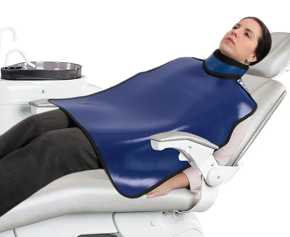 Mulher deitada em cadeira odontológica com avental de chumbo