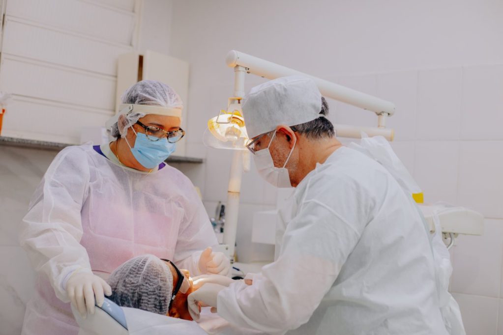 dentistas atendendo paciente em consultório branco