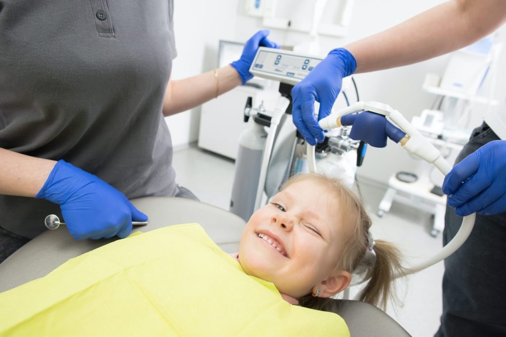 criança no dentista piscando um olho e sorrindo
