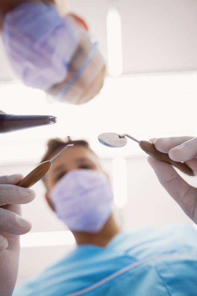 close-up de dentistas segurando suas ferramentas odontológicos acima do paciente