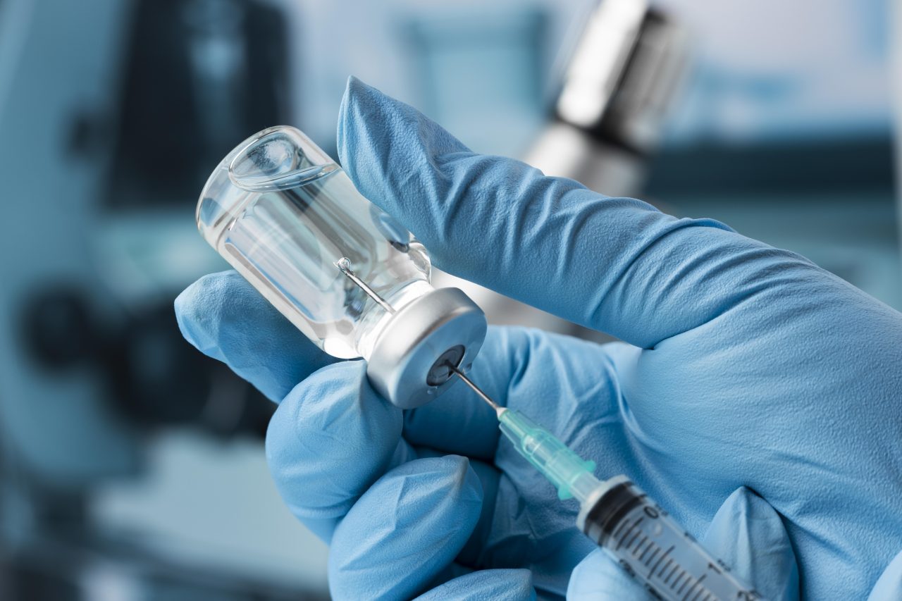 pessoa usando luva azul e pegando anestesia de vidrinho com a seringa