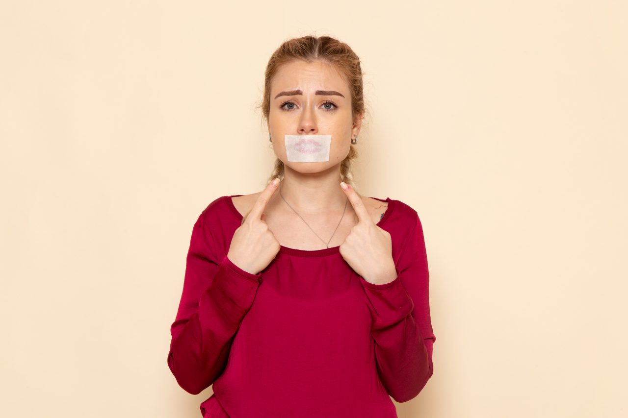 Mulher com boca tampada com esparadrapo.