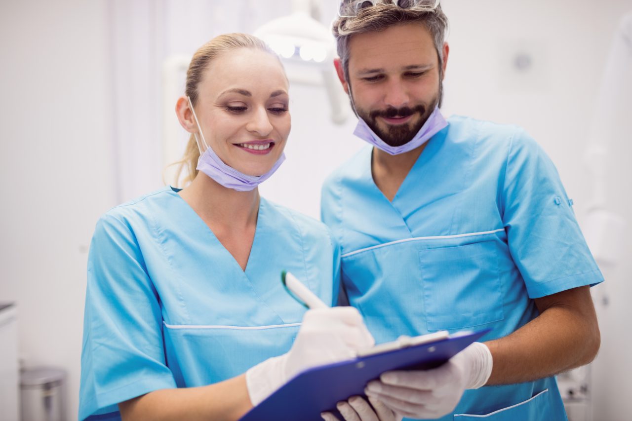 dentistas juntos sorrindo anotando em prancheta
