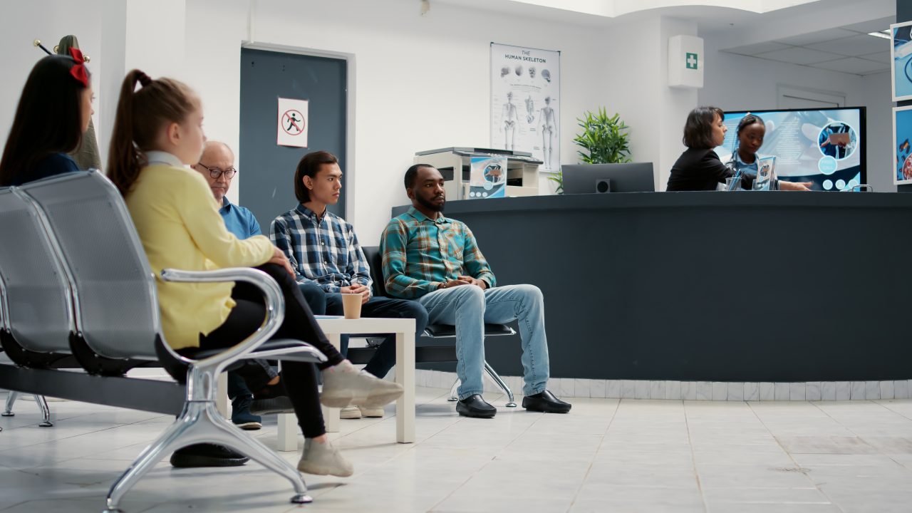 grupo de pessoas esperando sentados na recepção em uma clínica