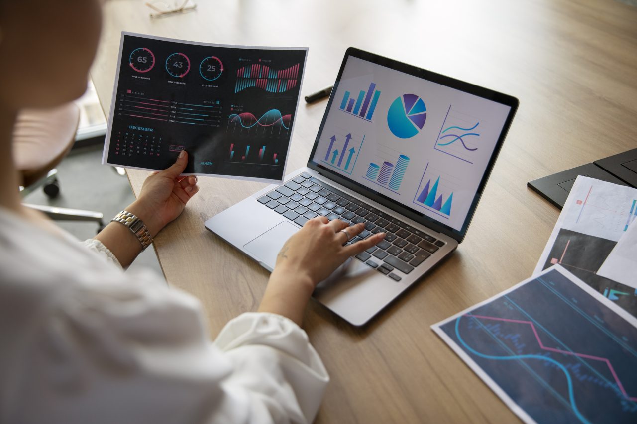 mulher olhando gráficos no computador e no papel