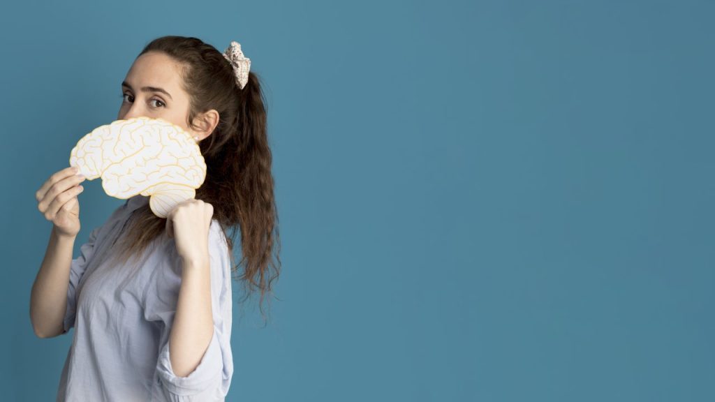Garota segurando um papel com formato de cérebro