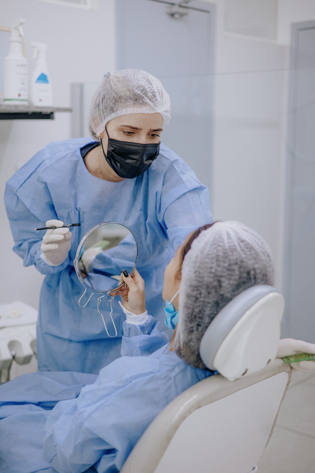 Dentista mostrando resultado para paciente pelo espelho