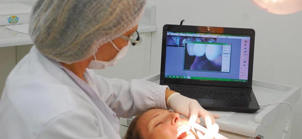 Dentista está realizando escaneamento intraoral em paciente e olhando os dentes no computador em tempo real