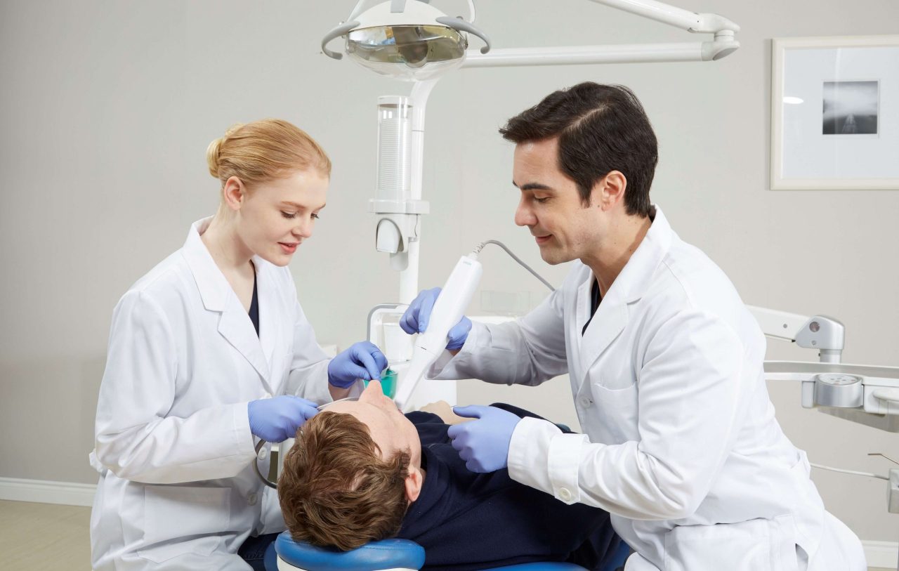 Dentista e assistente realizam escaneamento intraoral em paciente