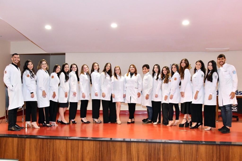 Cerimônia de Jaleco da PUC Goiás com os alunos enfileirados, todos usando jaleco.