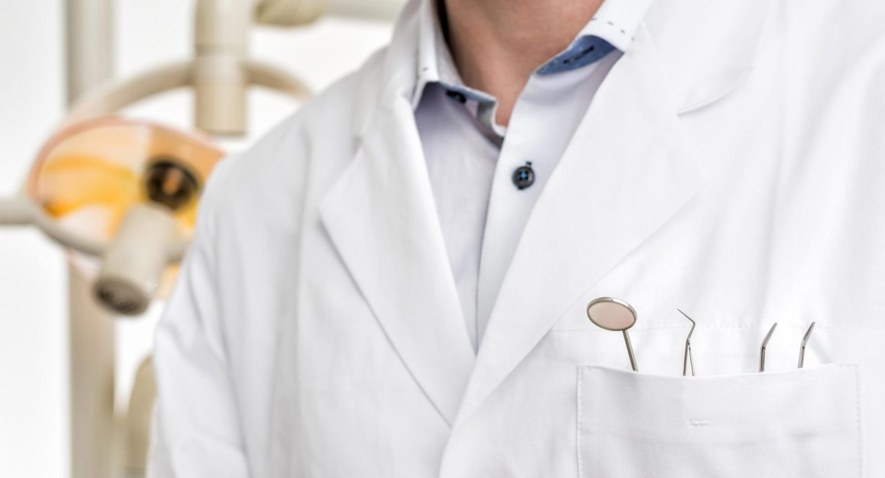 Imagem foca no bolso do jaleco do dentista, que está com seus instrumentos ali