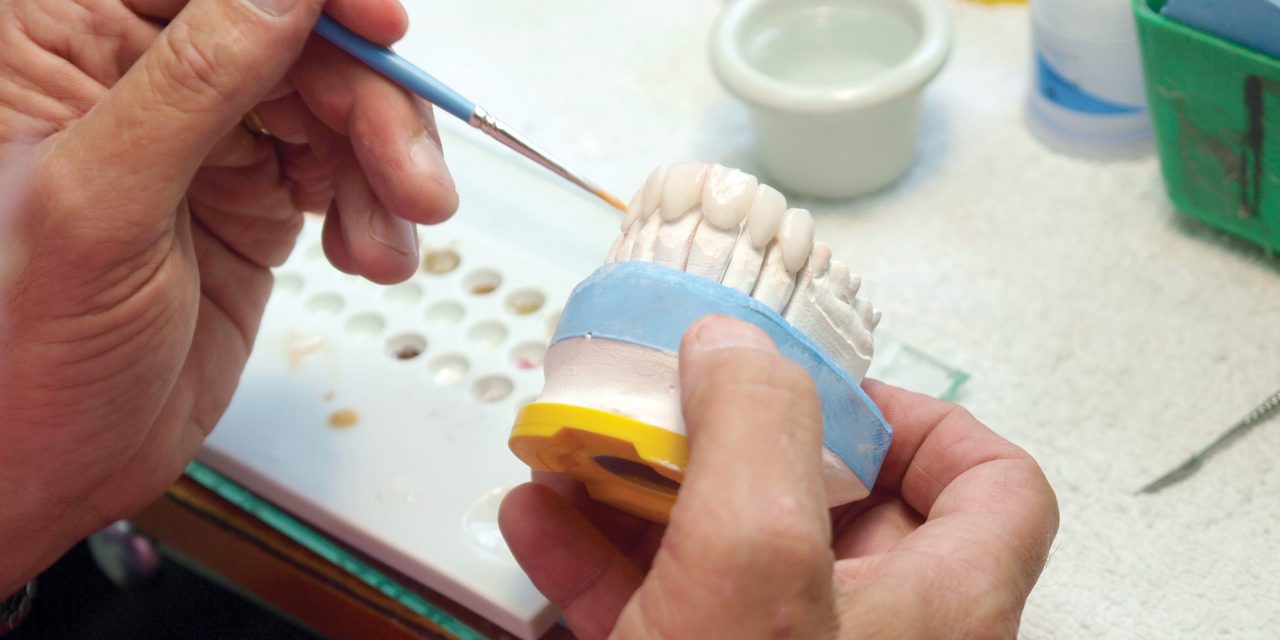 Dentista pintando molde de coroa dentária