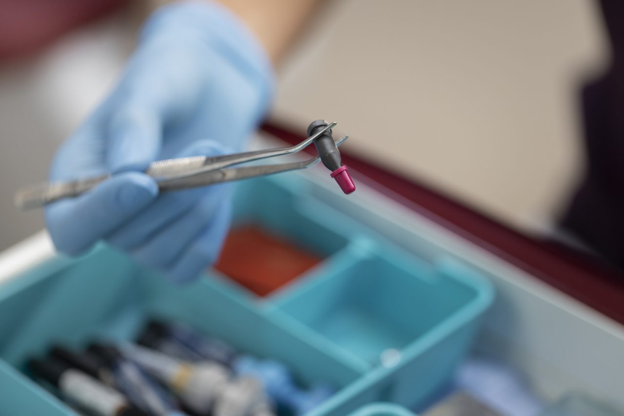 dentista pegando algo com a pinça de caixa azul