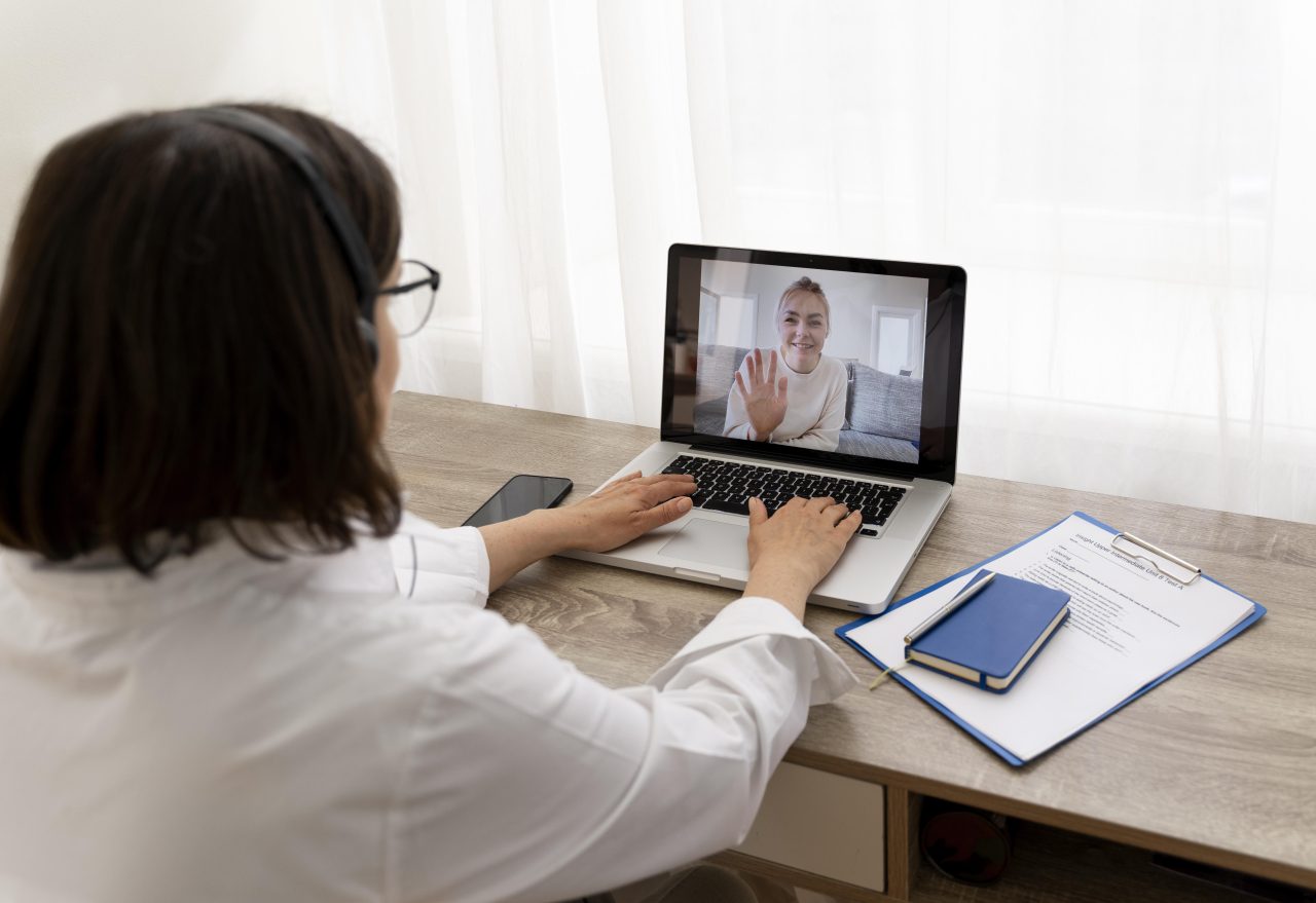Mulher sentada em frente a um notebook atendendo paciente por videochamada