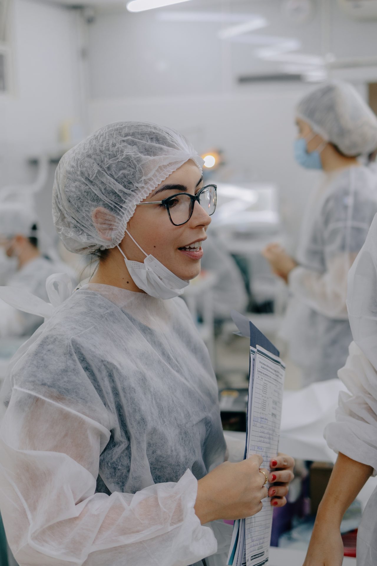 Aluna dentista da EAP Goiás conversando, ela está segurando alguns papéis e está paramentada com os EPIs