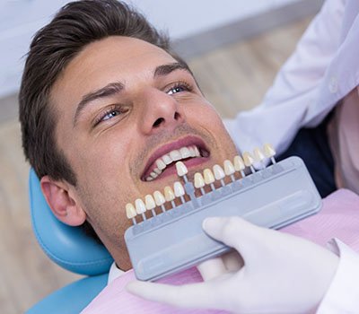 Dentista testando faceta em dente de paciente.