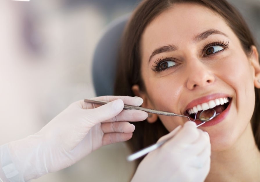 Mulher feliz tendo seus dentes examinados por dentista