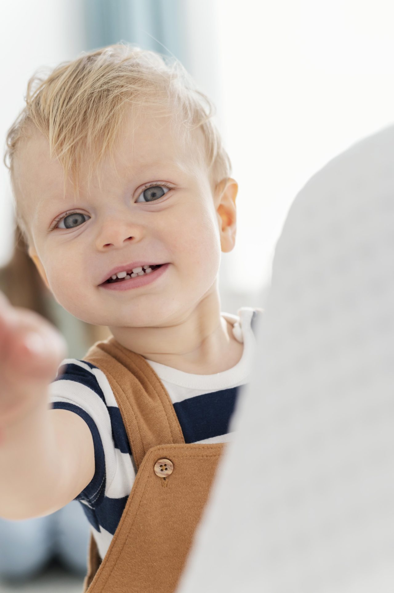 Bebê loiro e de olhos verdes sorrindo para a câmeta