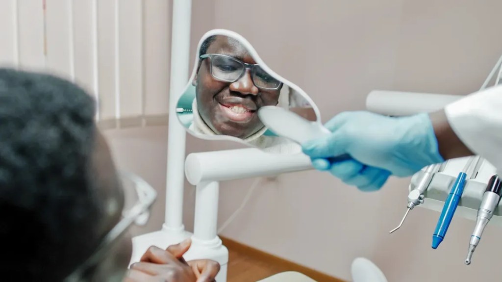 paciente se vendo em espelho que o dentista está mostrando