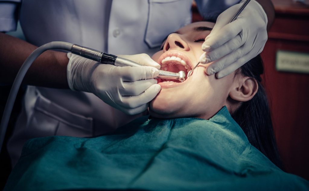 Dentista fazendo tratamento em dentes de paciente mulher