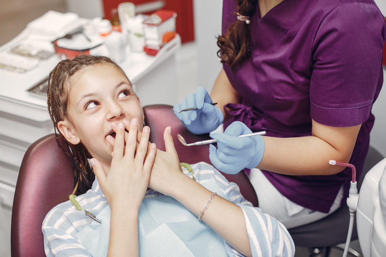adolescente tampando a boca e olhando para dentista.