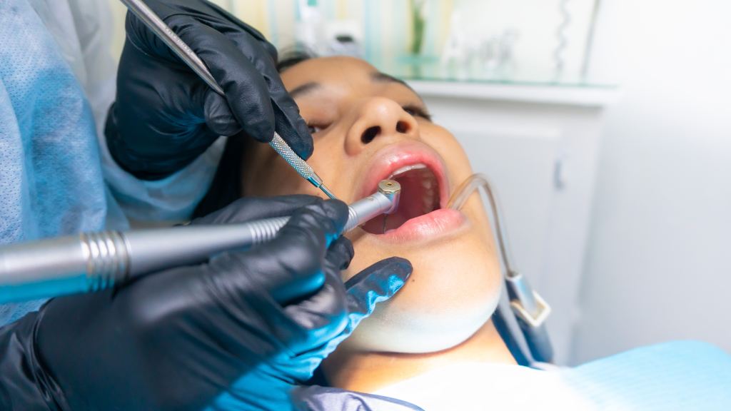 paciente no dentista com boca aberta recebendo tratamento