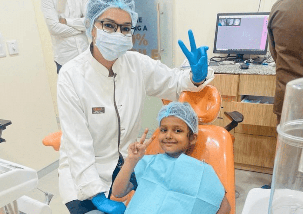 Dentista e seu paciente criança estão posando para câmera fazendo sinal de paz e amor. - para atender crianças é preciso especializar em odontopediatria.