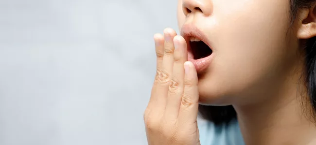 Mulher checando se está com mau hálito