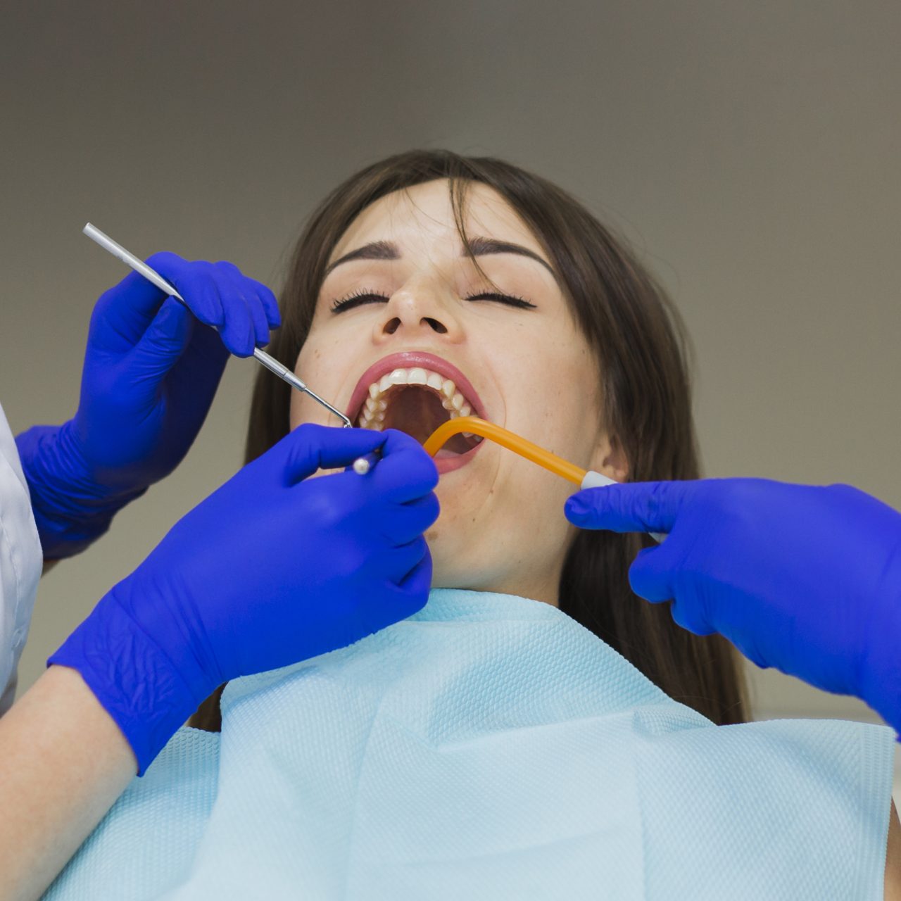 Dentistas fazendo limpeza em dente de paciente
