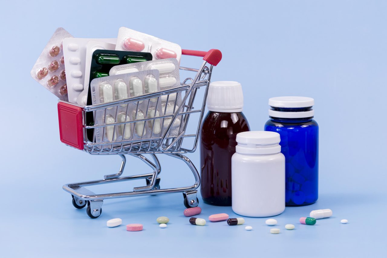 vários potes de medicamentos, um mini carrinho de supermercado e remédios espalhados no chão