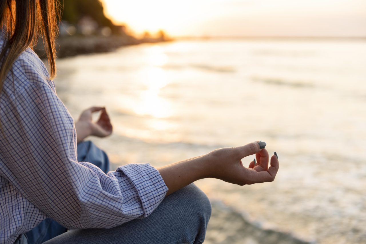 Mulher meditando sentada na areia na praia