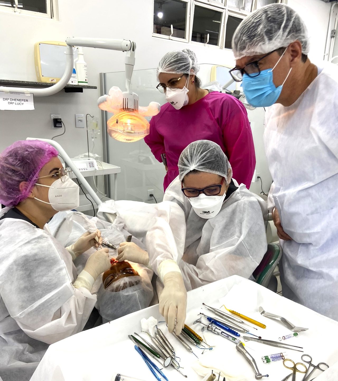 Quatro Alunos da EAP Goiás na clínica escola de odontologia realizando procedimentos em paciente.