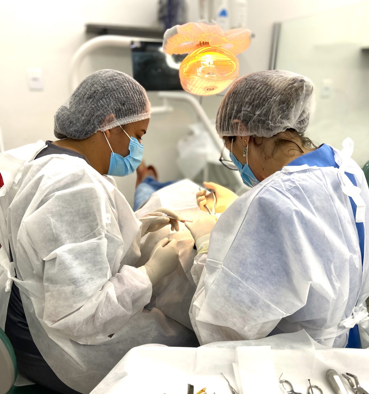 Duas alunas da EAP Goiás na clínica escola de odontologia realizando procedimentos em paciente.