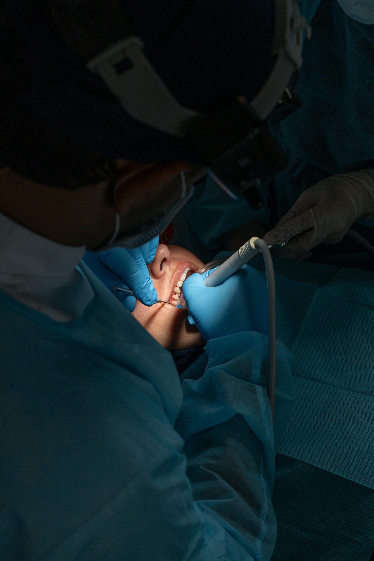 Dentista e assistente realizando cirurgia em dente de paciente.