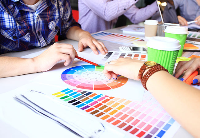 Time de marketing decidindo identidade visual. Com uma paleta de cores no centro e amostras em volta.