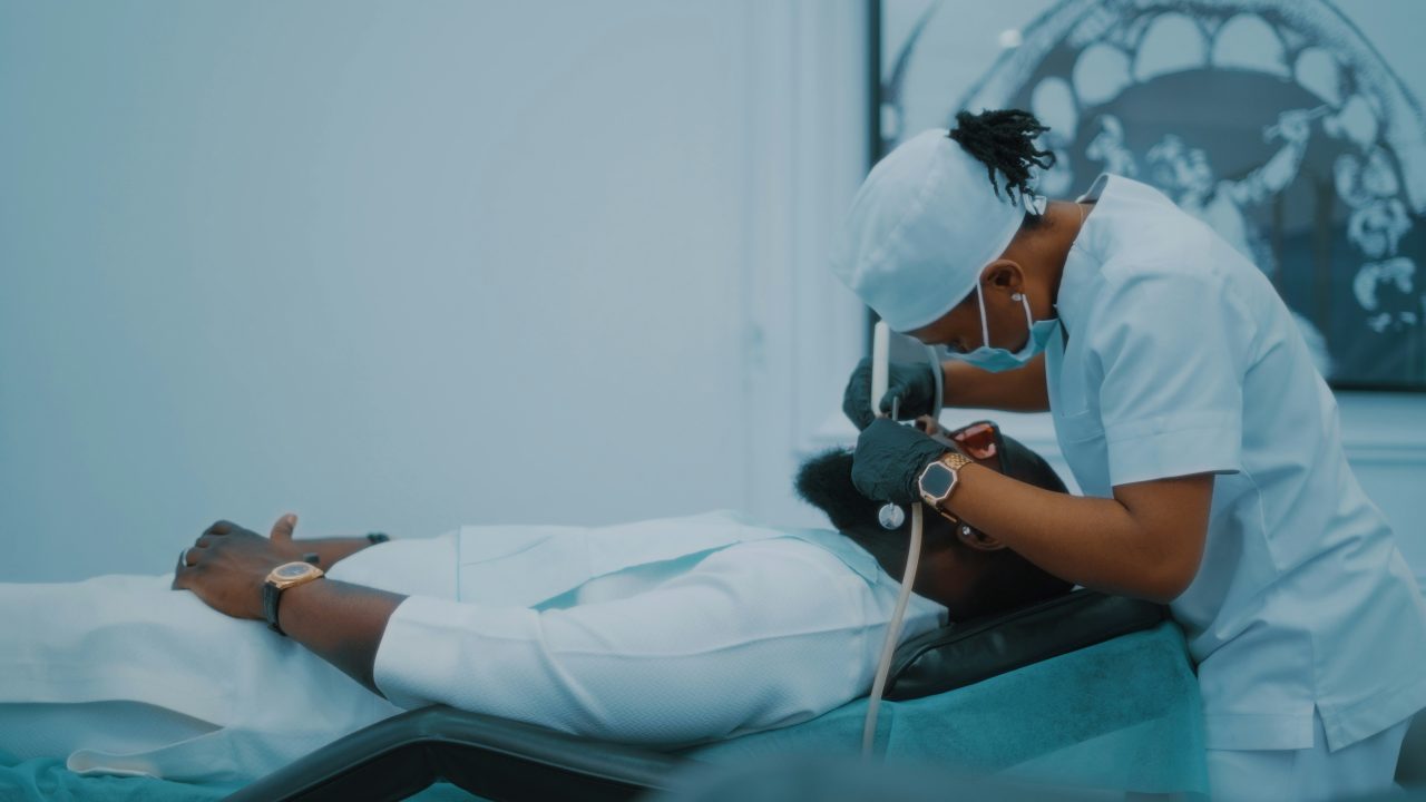 Dentista está fazendo procedimento odontológico em paciente.