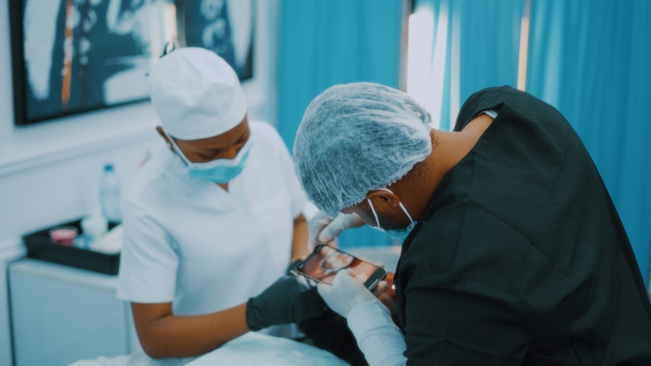 Dentista e assistente estão tirando foto de resultado do procedimento do paciente.